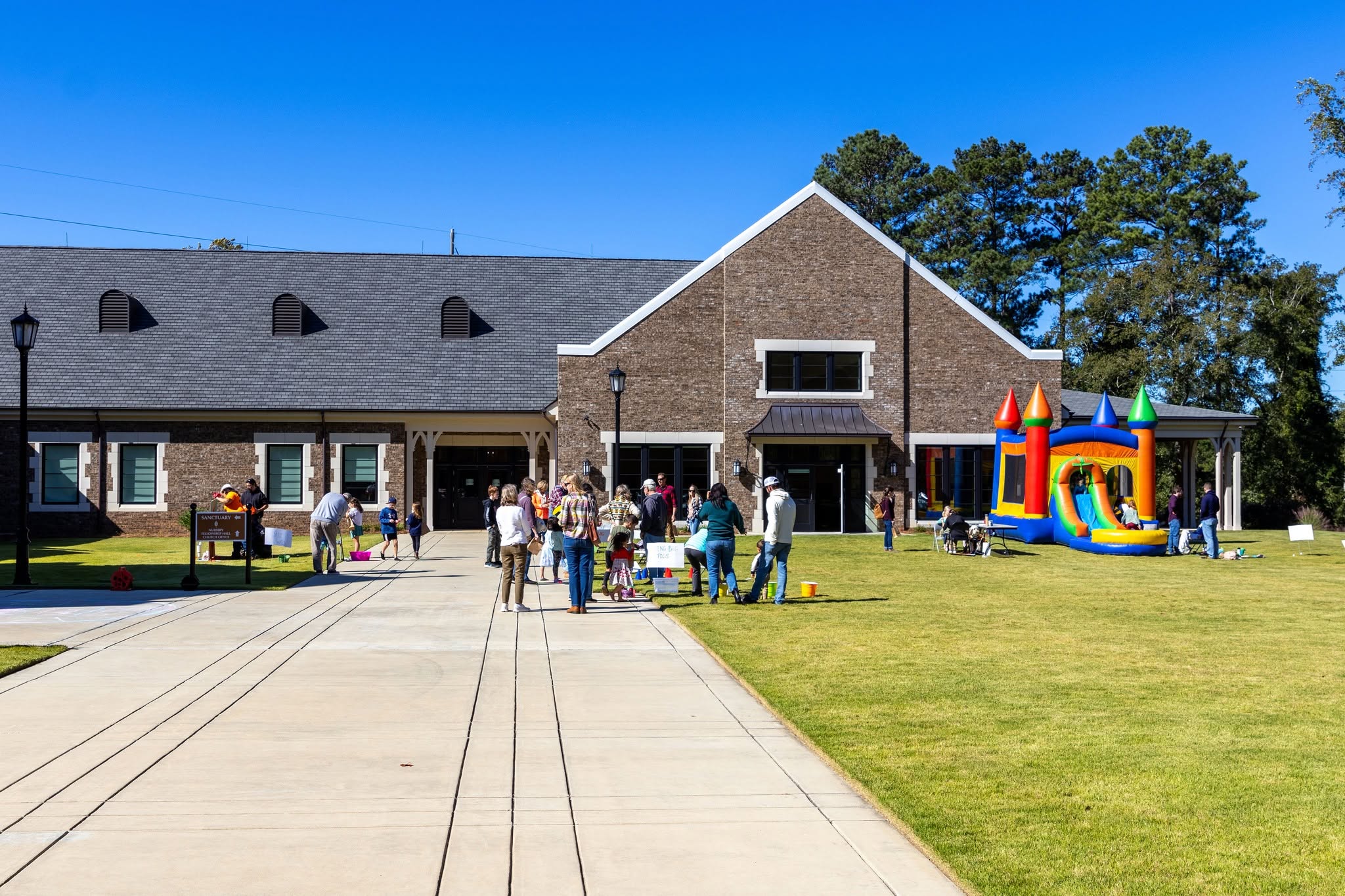 The fall festival on the lawn: families, a bounce house, the church behind